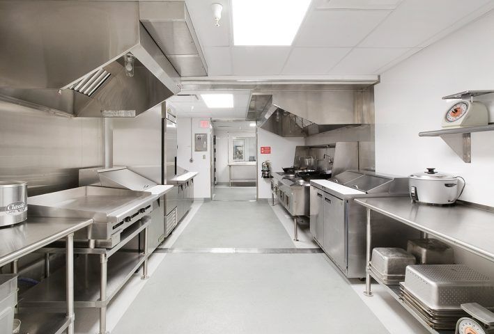 Una cocina comercial vacía con electrodomésticos y encimeras de acero inoxidable.