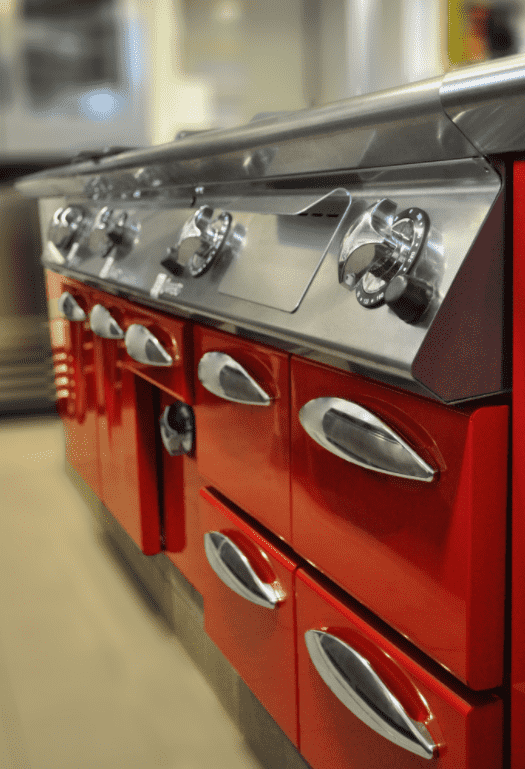 Una cocina con gabinetes rojos y electrodomésticos de acero inoxidable.