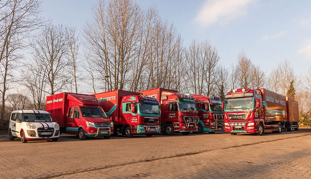 Auf einem Parkplatz steht eine Reihe roter Lastwagen und Lieferwagen.