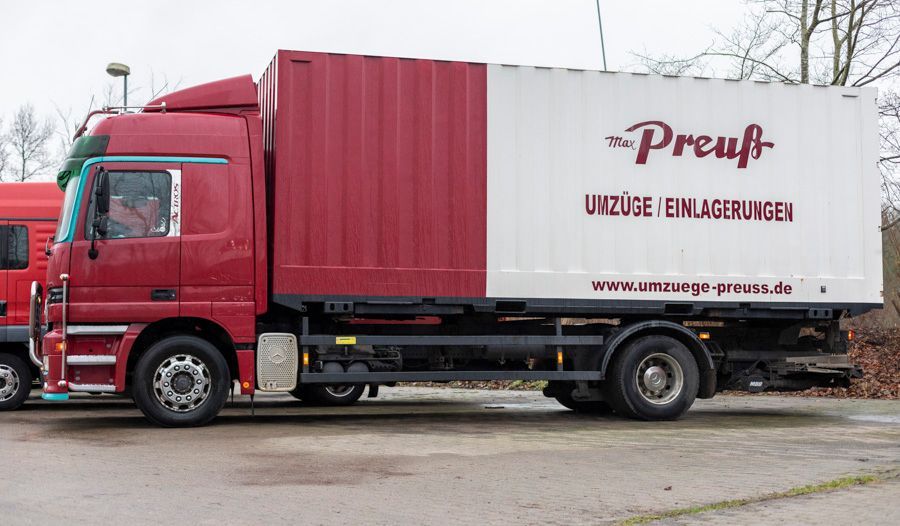 Ein rot-weißer Preuß-LKW steht auf einem Parkplatz