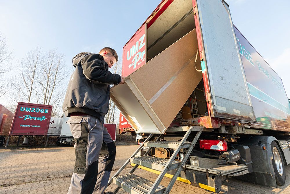 Ein Mann lädt eine Kiste auf die Ladefläche eines Lastwagens.