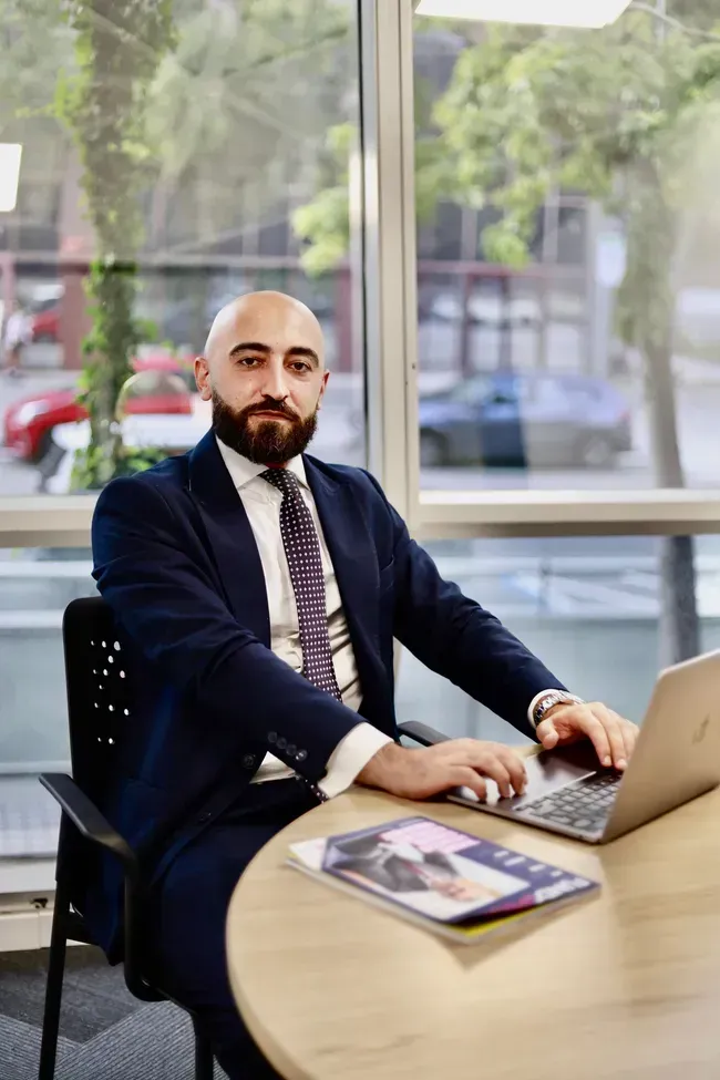 Dos hombres vestidos de negocios revisan papeles en una mesa en una oficina.