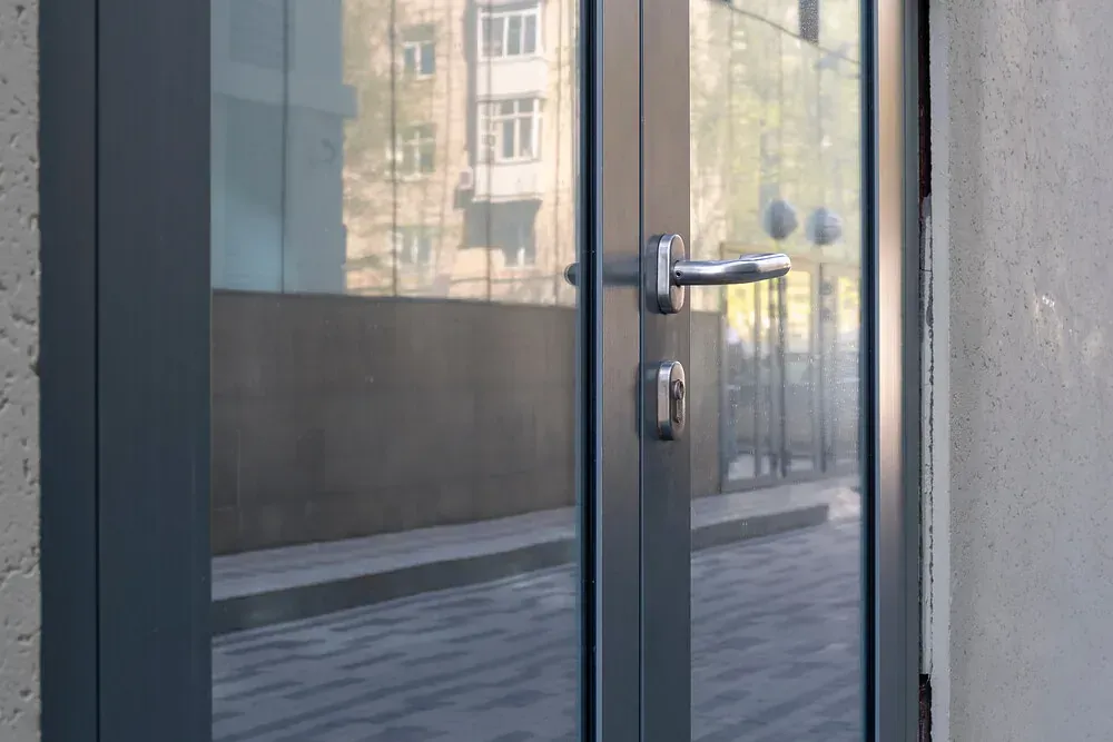 Un primer plano de una puerta con el reflejo de un edificio en ella.