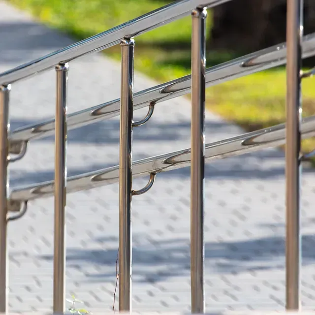 Un primer plano de una barandilla de acero inoxidable en una acera.