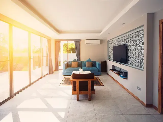 Una sala de estar con sofá, silla, mesa y televisión.