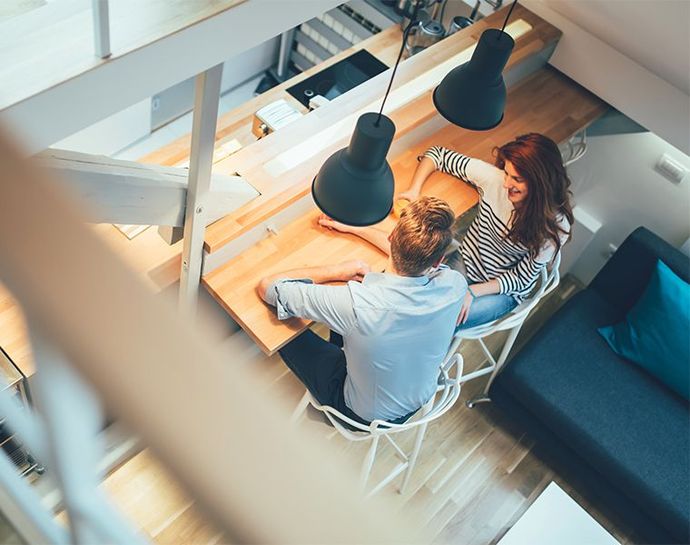 Couple assis à la partie bar de la cuisine dans une maison rénovée