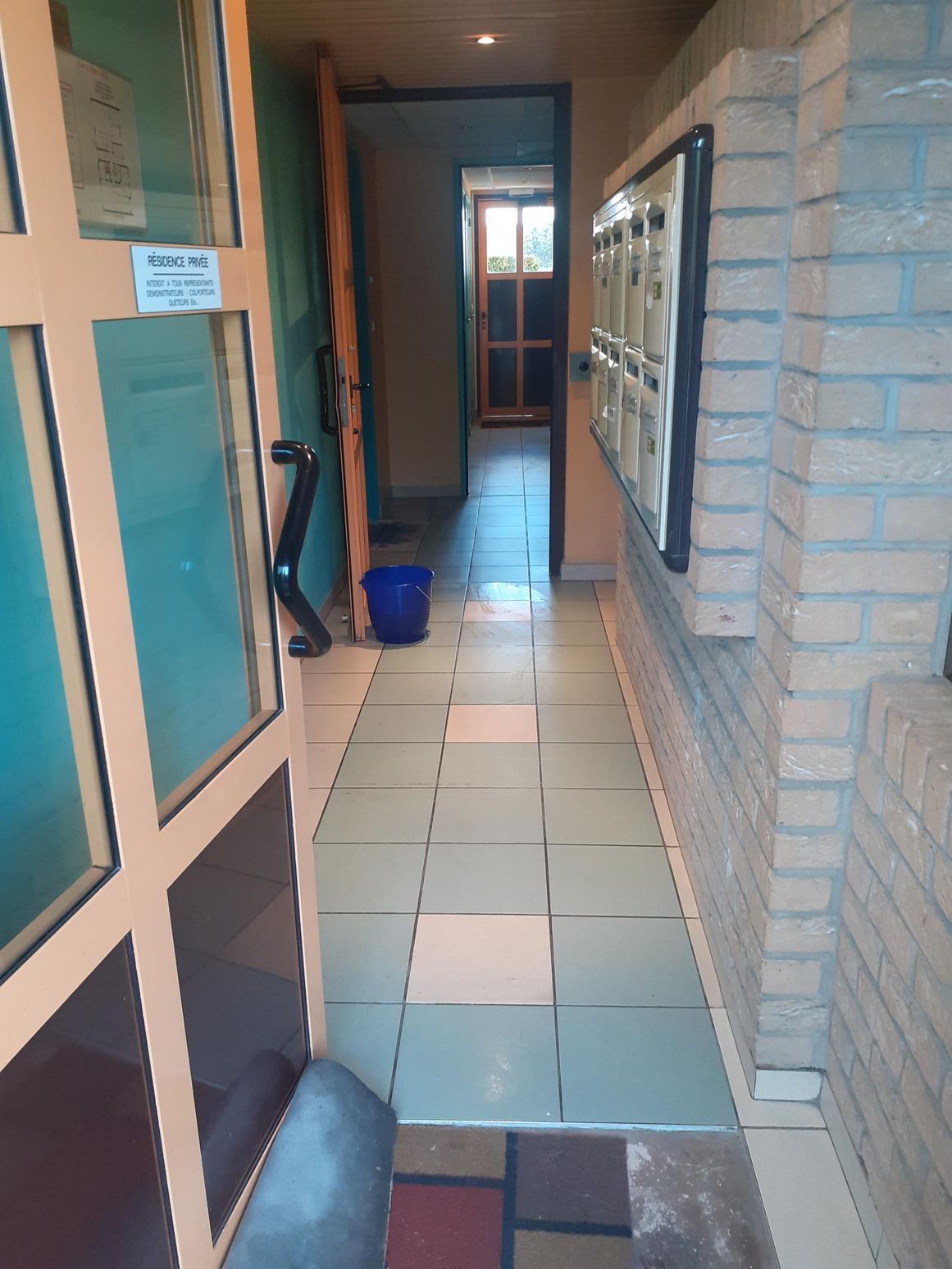 Hall d'entrée, carrelage bicolore, seau de nettoyage