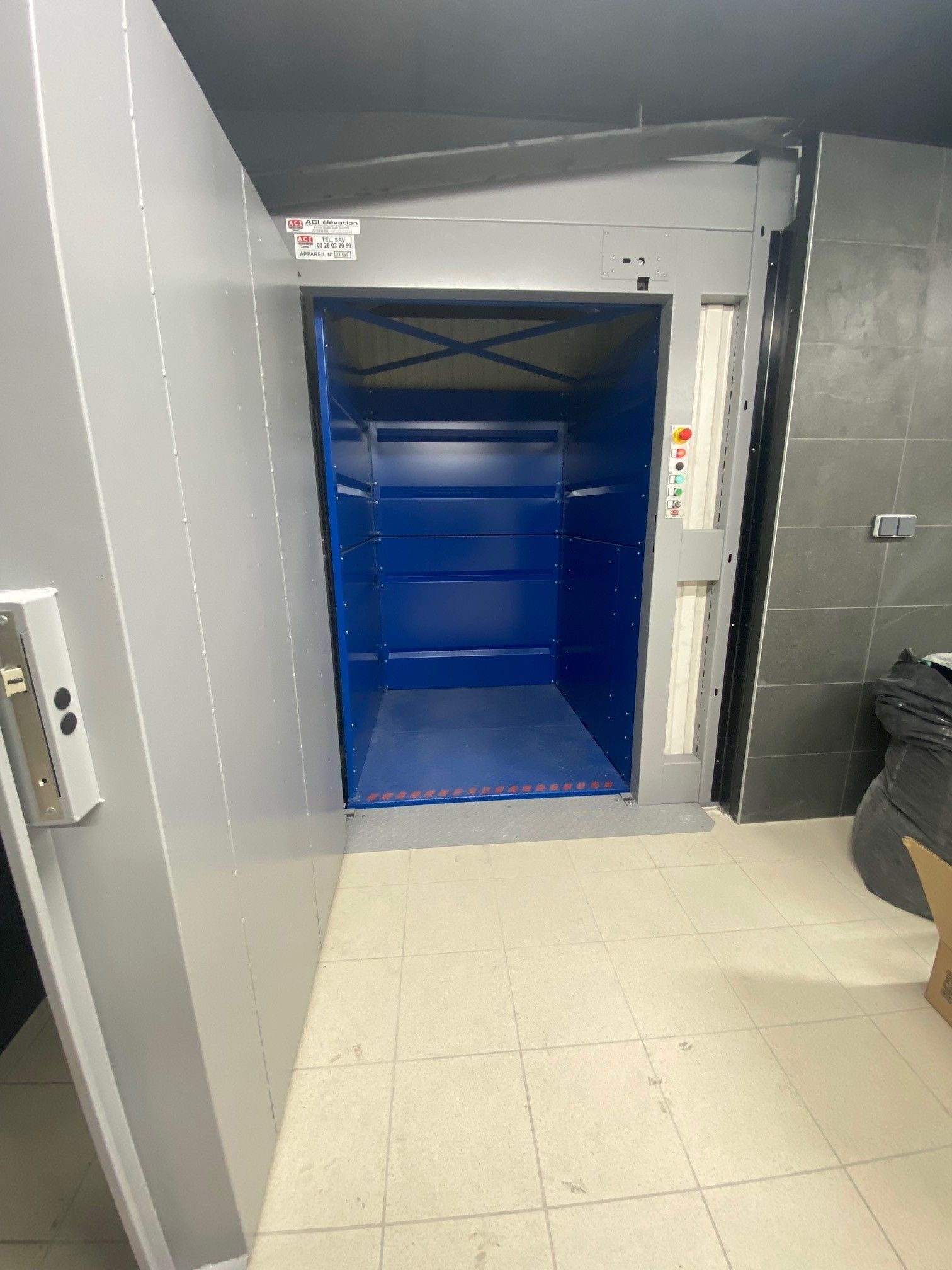 Ascenseur de fret industriel ouvert avec intérieur bleu.