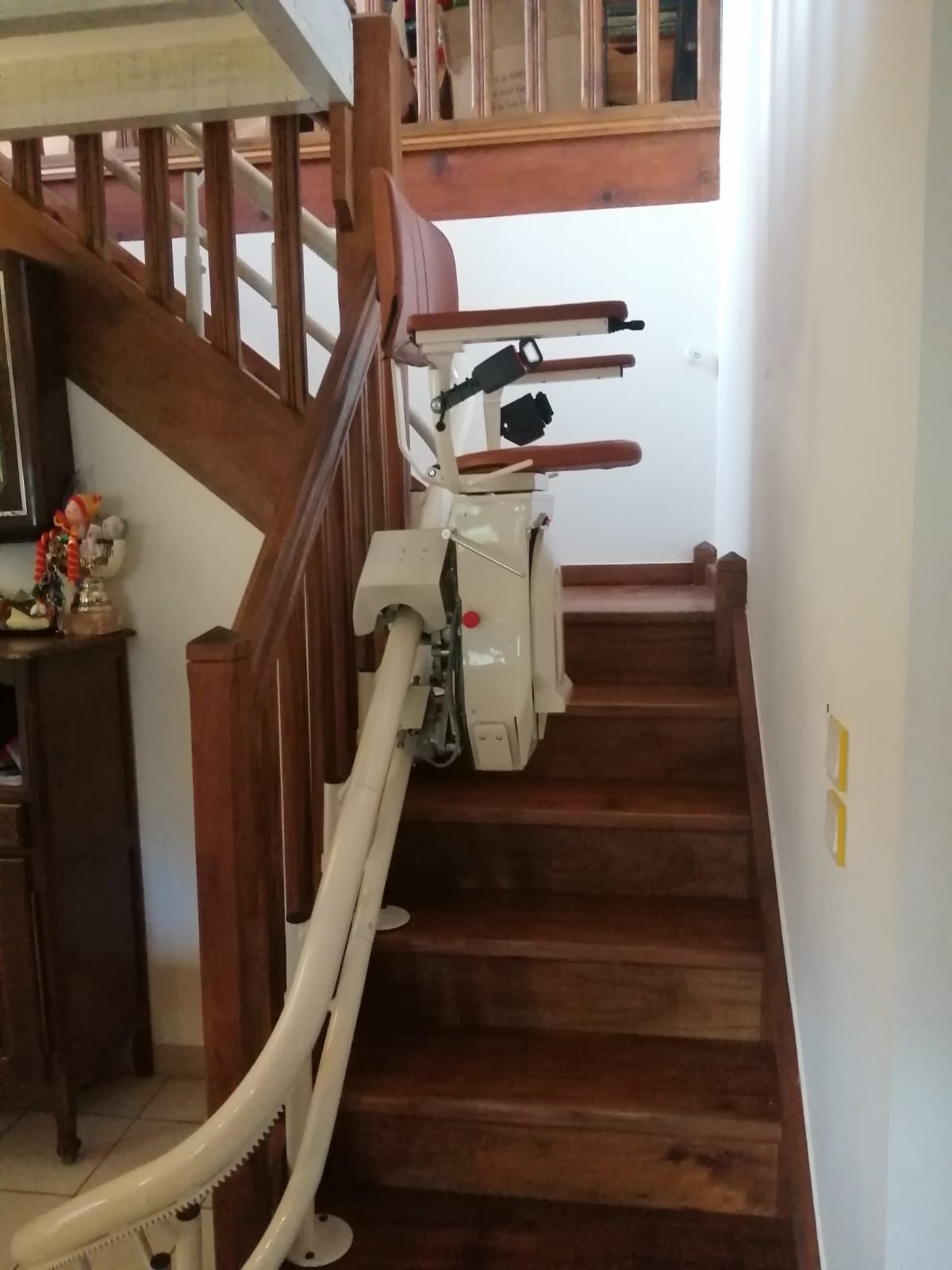 Monte-escalier installé sur un escalier en bois dans une maison. Le monte-escalier est blanc.