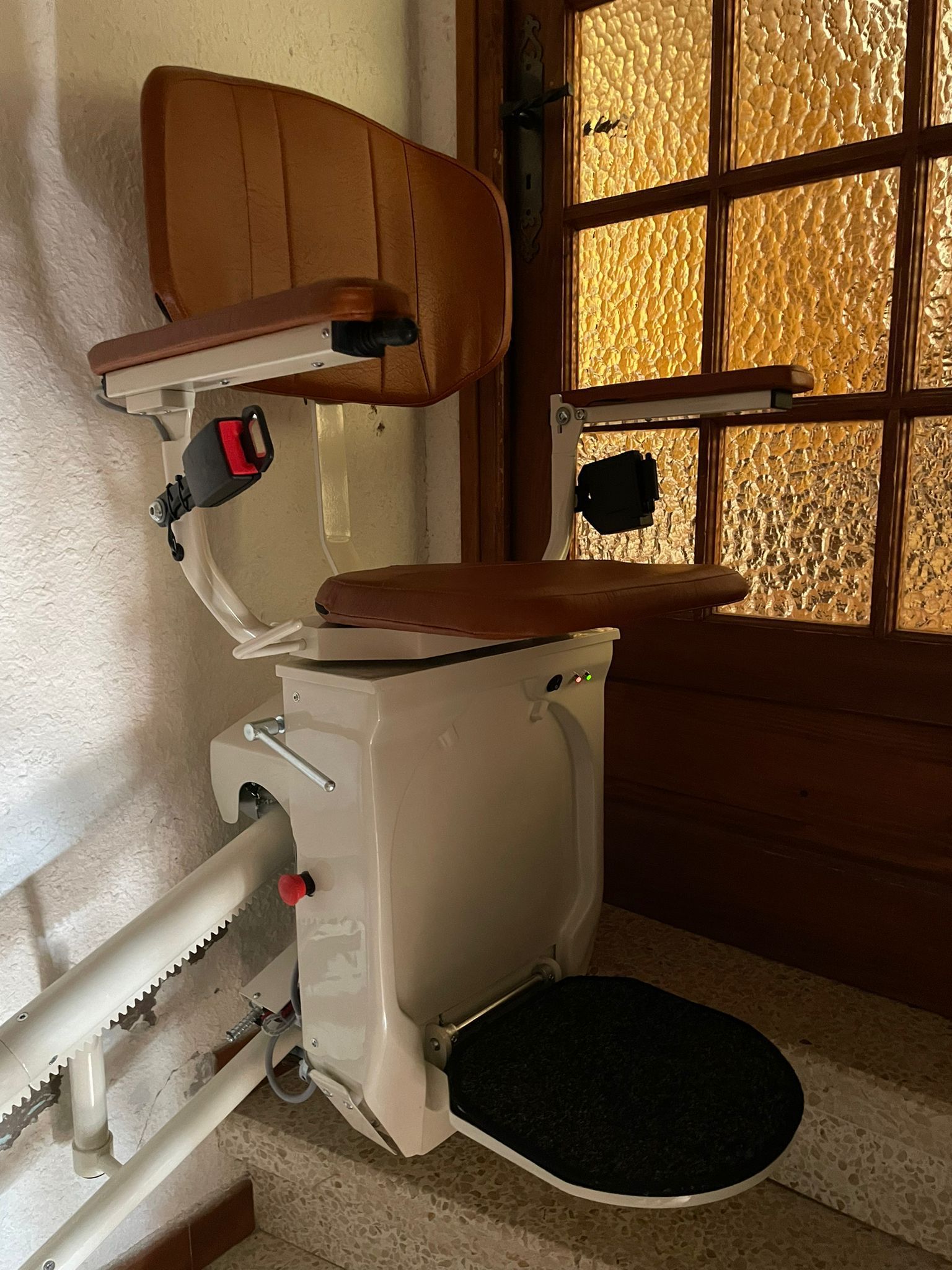 Salle de bains avec toilettes blanches et siège noir à côté d'un lavabo mural et de stores en bois.