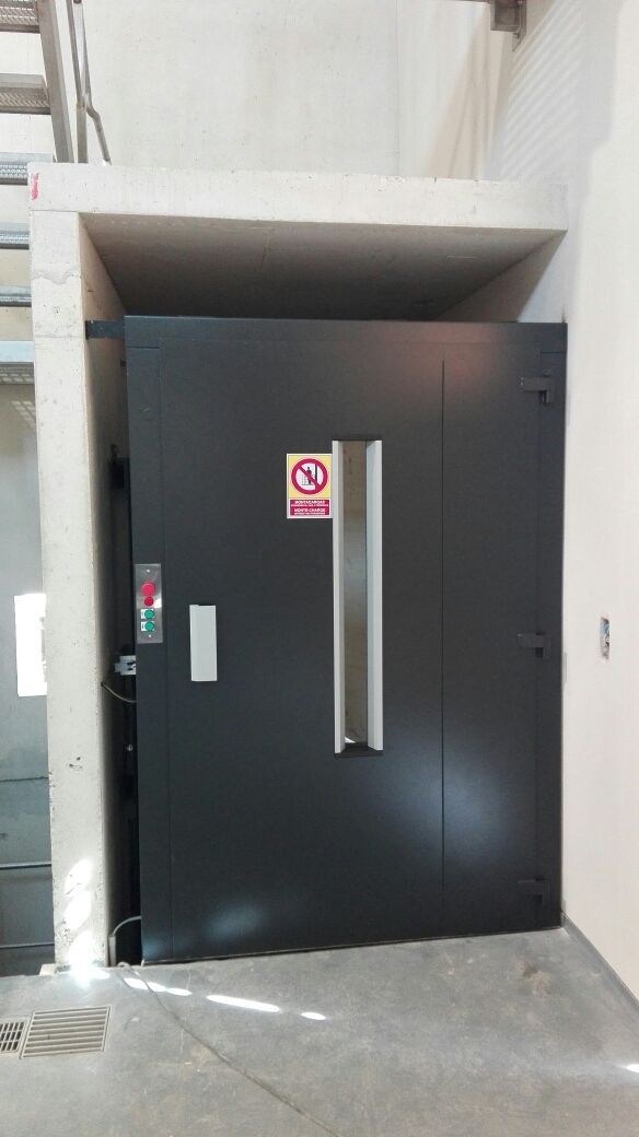 Porte d'ascenseur sombre avec fenêtre étroite et panneau Interdit de fumer dans une alcôve en béton.