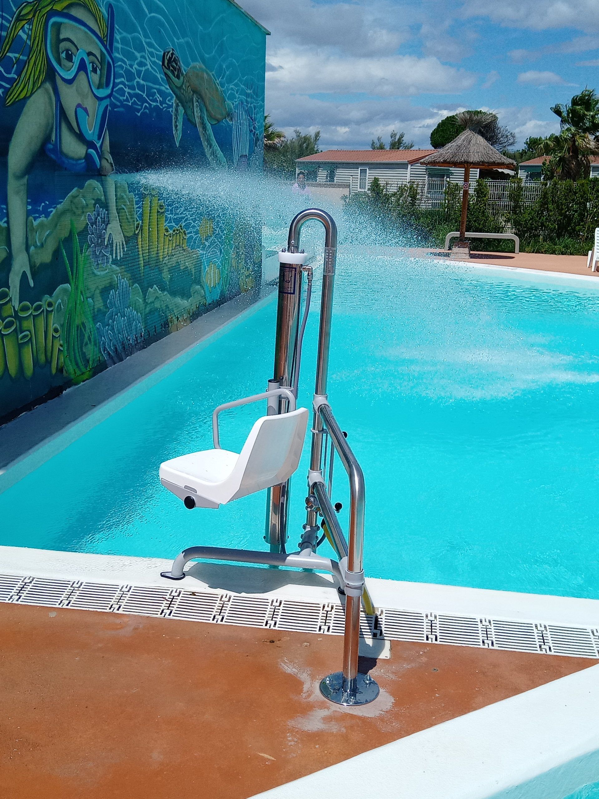 Dispositif de mise à l'eau dans une piscine turquoise, ornée d'une fresque de dauphins et d'une fontaine à jets d'eau.