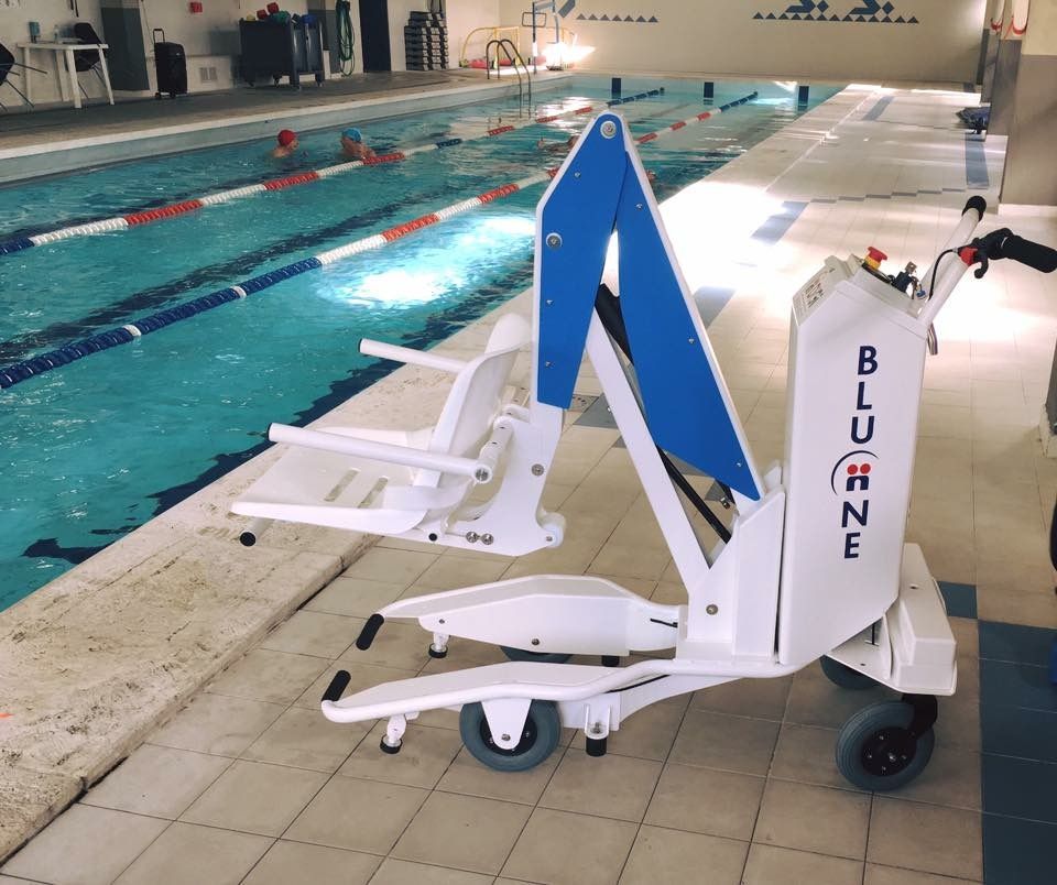 Un élévateur de piscine blanc et bleu est installé sur le bord d'une piscine. L'élévateur est équipé d'un siège et se trouve à proximité de la piscine.