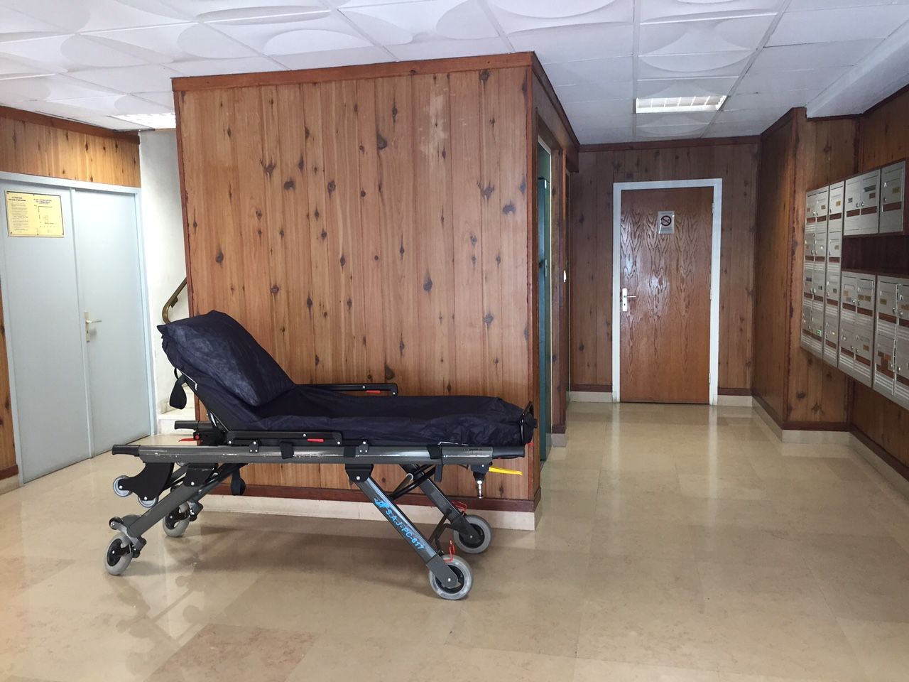 Couloir d'hôpital avec une civière d'examen noire et des murs lambrissés