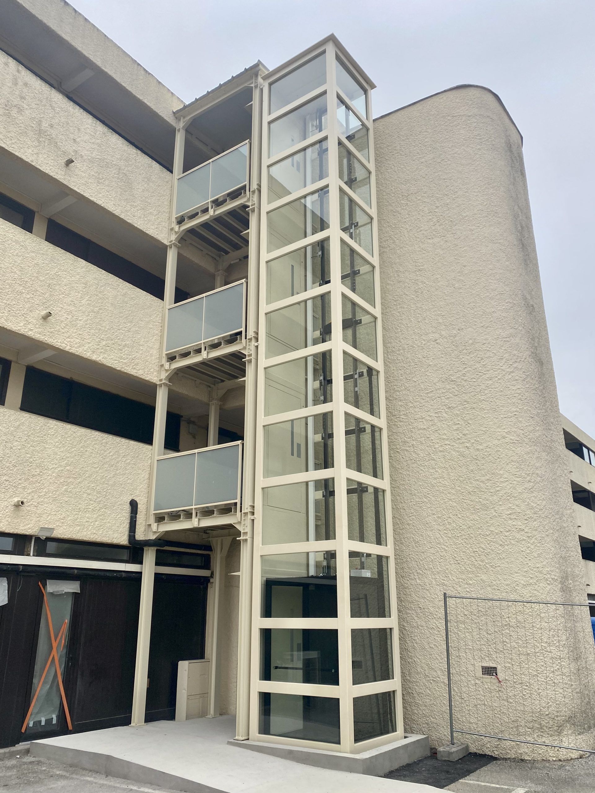 Extérieur d'un immeuble moderne avec une cage d'ascenseur vitrée et des balcons