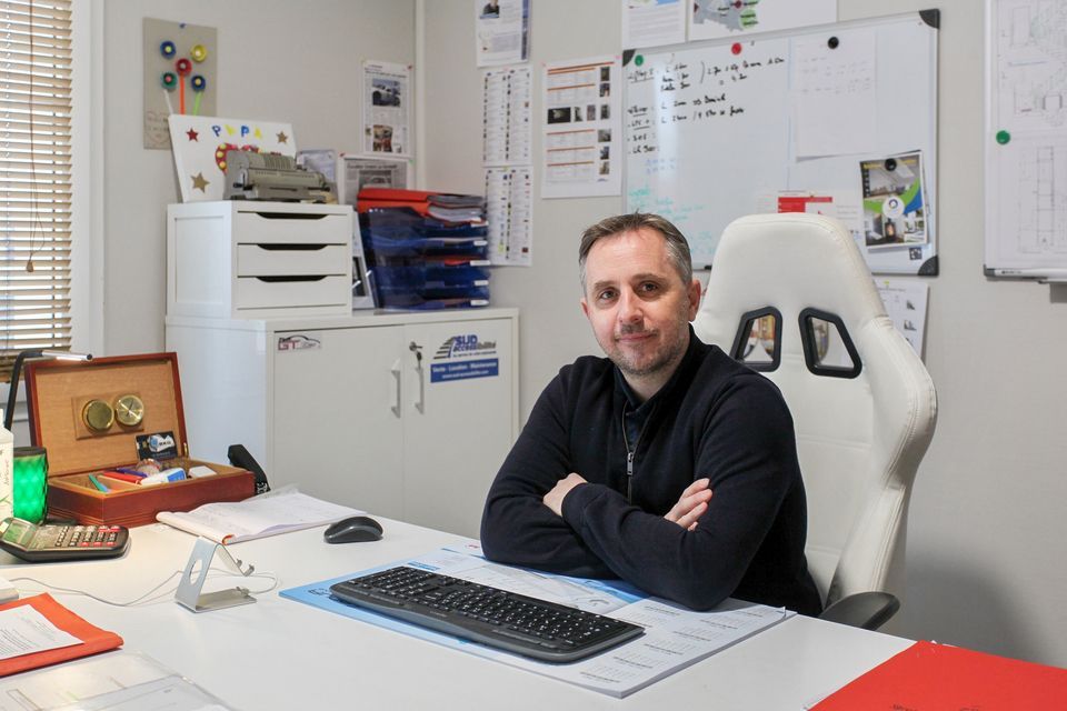 Un homme assis à un bureau dans un bureau lumineux, avec un clavier d'ordinateur.
