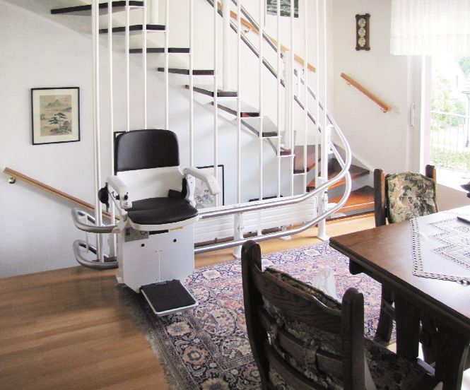 Un monte-escalier situé à côté d'un escalier courbe à l'intérieur d'une maison permet d'accéder aux personnes à mobilité réduite.
