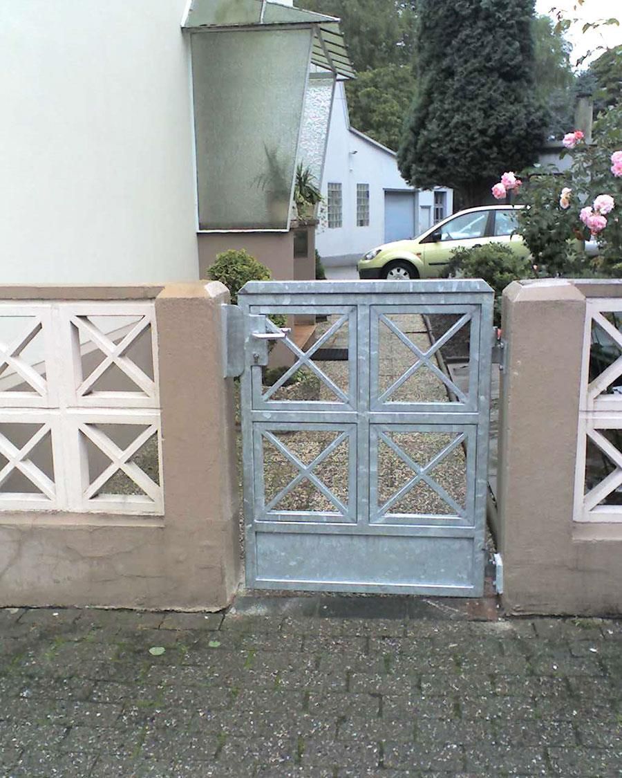 Ein gelbes Auto parkt vor einem Haus hinter einem Tor.