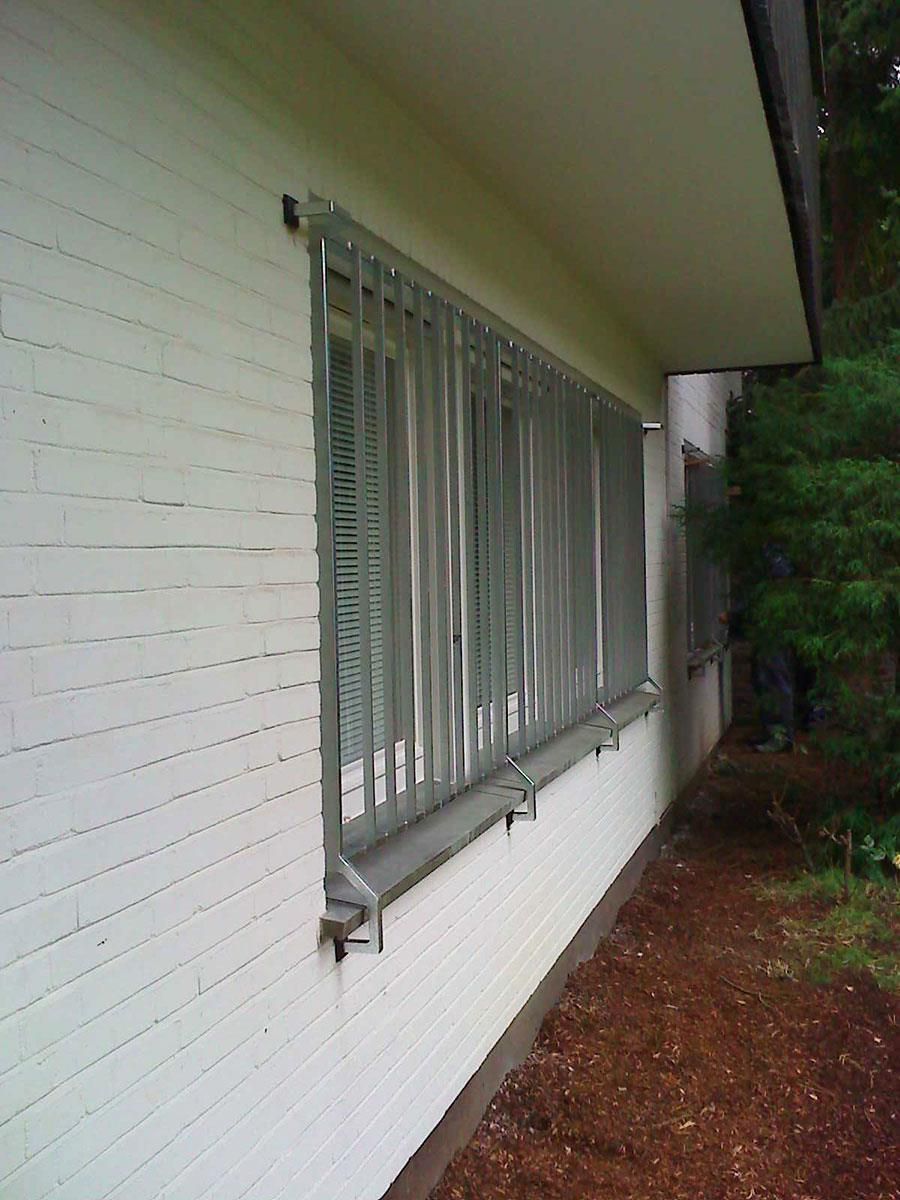 Ein weißes Backsteingebäude mit einem Metallzaun um die Fenster