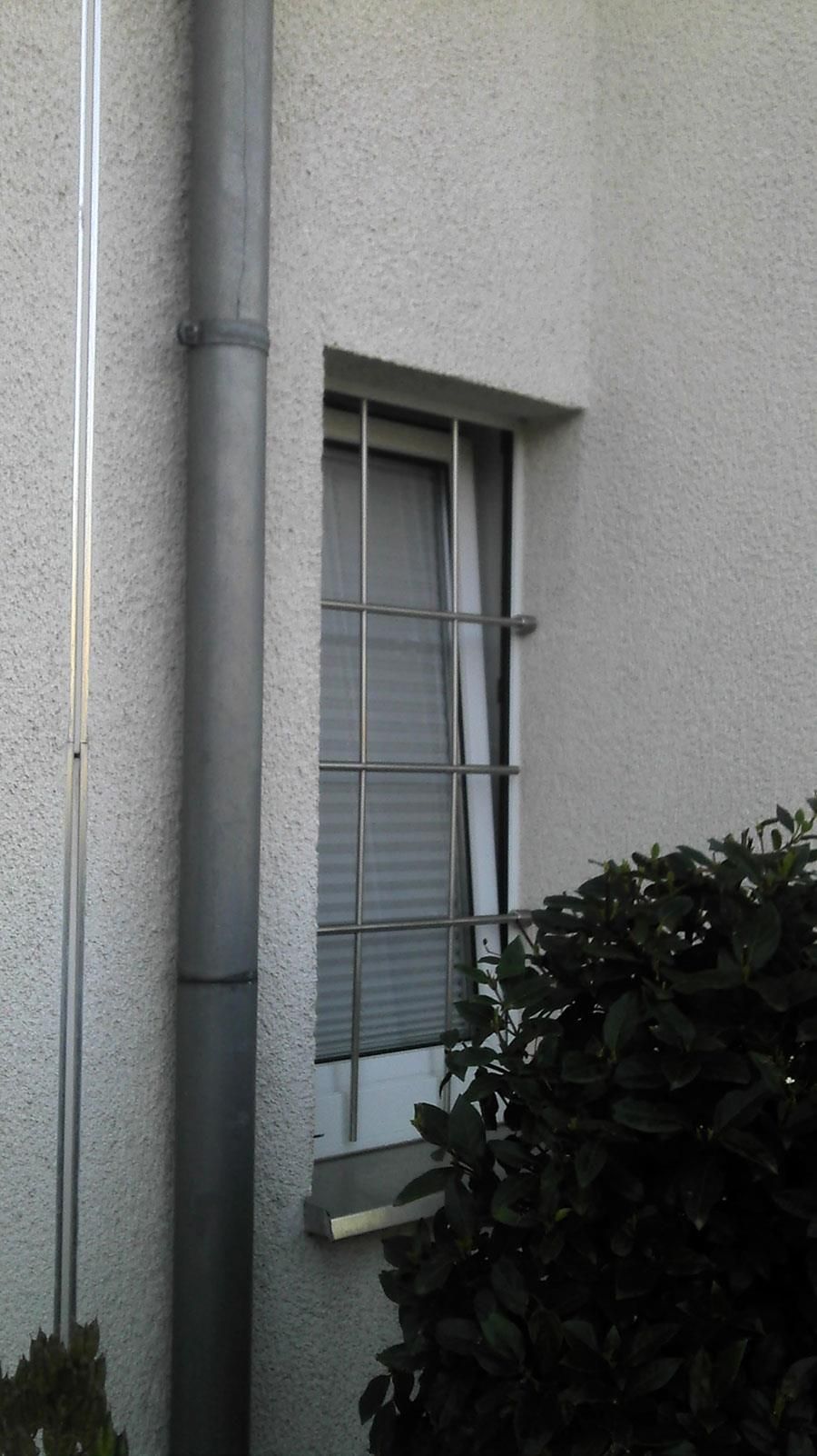 An der Seite eines Gebäudes befindet sich ein vergittertes Fenster.