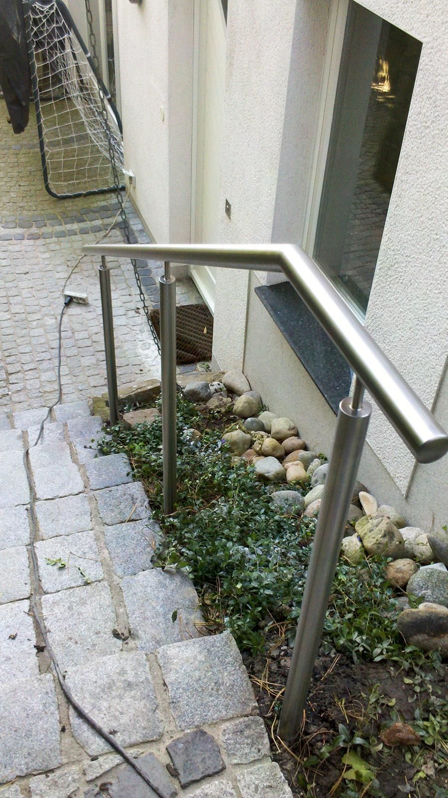 Eine Treppe mit einem Edelstahlgeländer, die zu einem Gebäude hinaufführt.