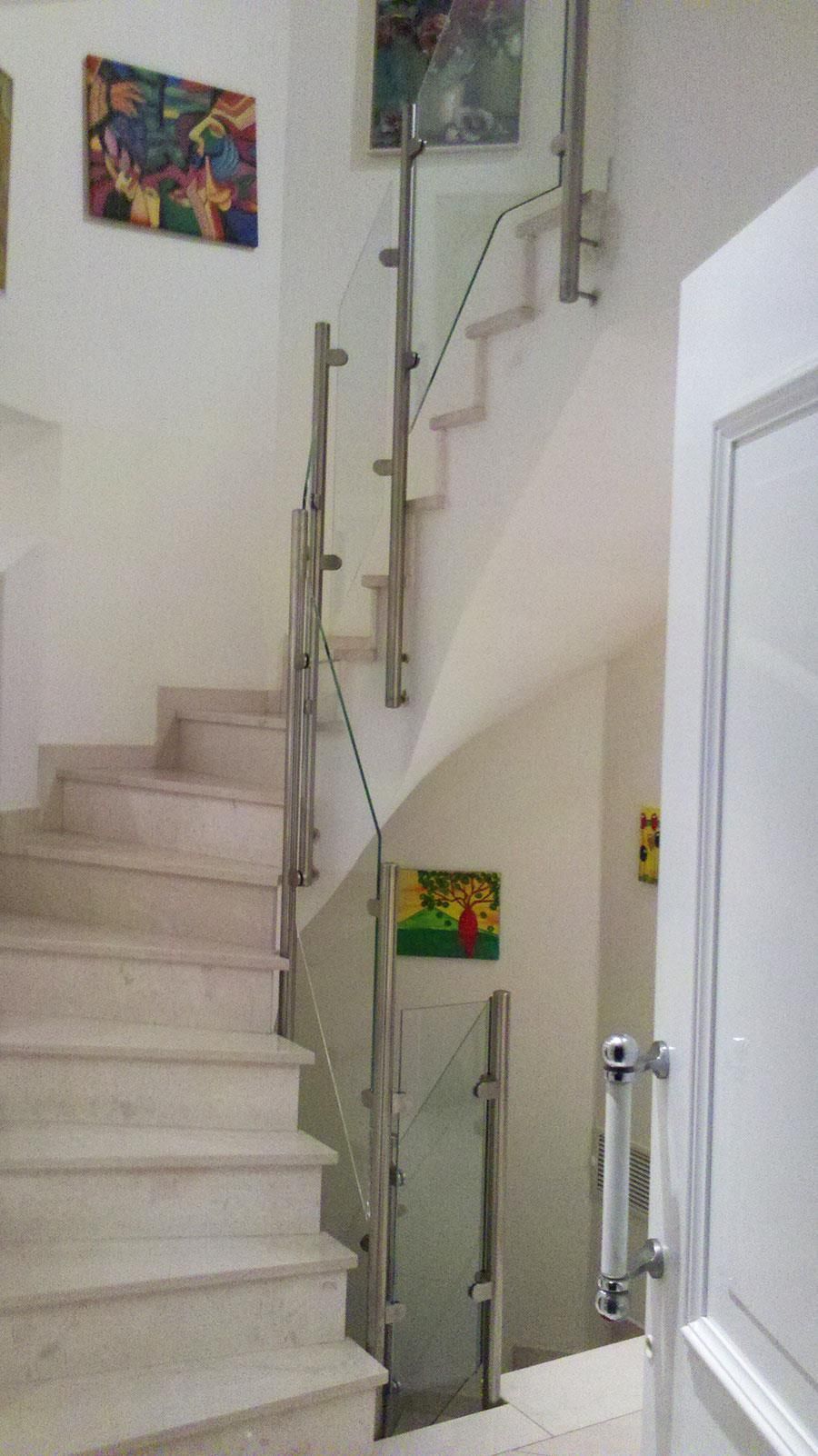Eine Treppe mit einem Glasgeländer und einem Gemälde an der Wand