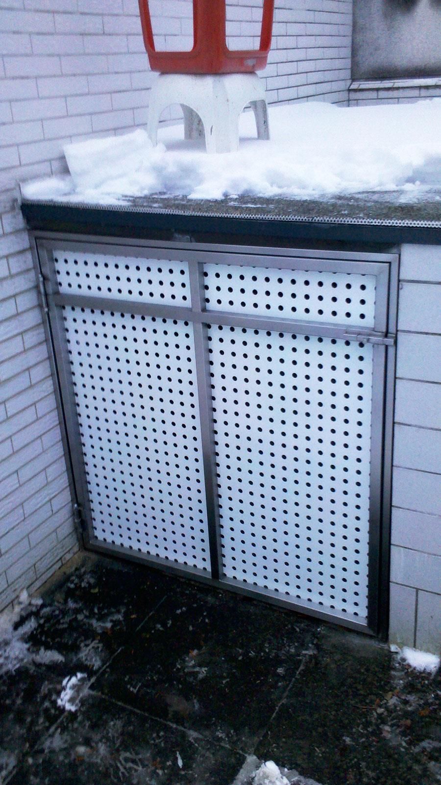 Ein Edelstahlschrank mit Löchern darin ist mit Schnee bedeckt.