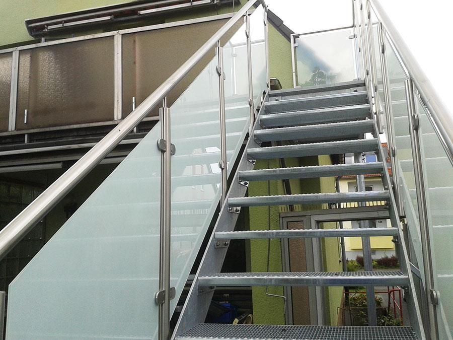 Eine Treppe mit Glasgeländer, die zu einem Balkon führt