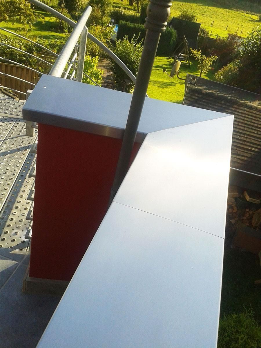 Ein Balkon mit einem roten Kamin und einem weißen Tisch