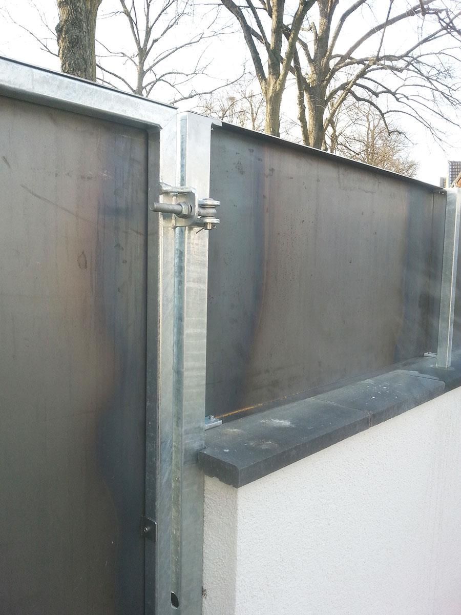 Eine Nahaufnahme eines Metallzauns mit Bäumen im Hintergrund.