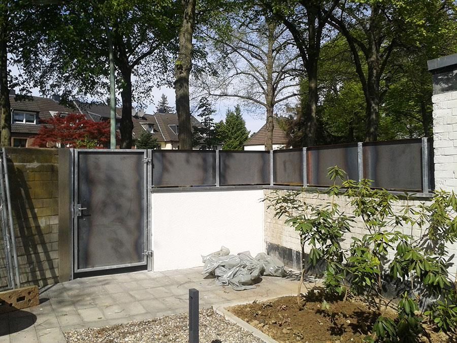 Ein Zaun mit einem Tor und Bäumen im Hintergrund