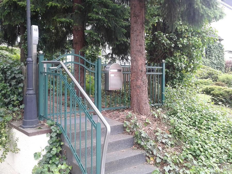 Treppe führt hinauf zu einem Tor mit einem Briefkasten im Hintergrund