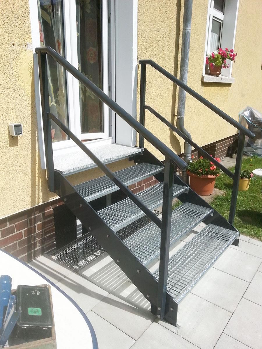 Eine Metalltreppe, die zu einem gelben Haus führt