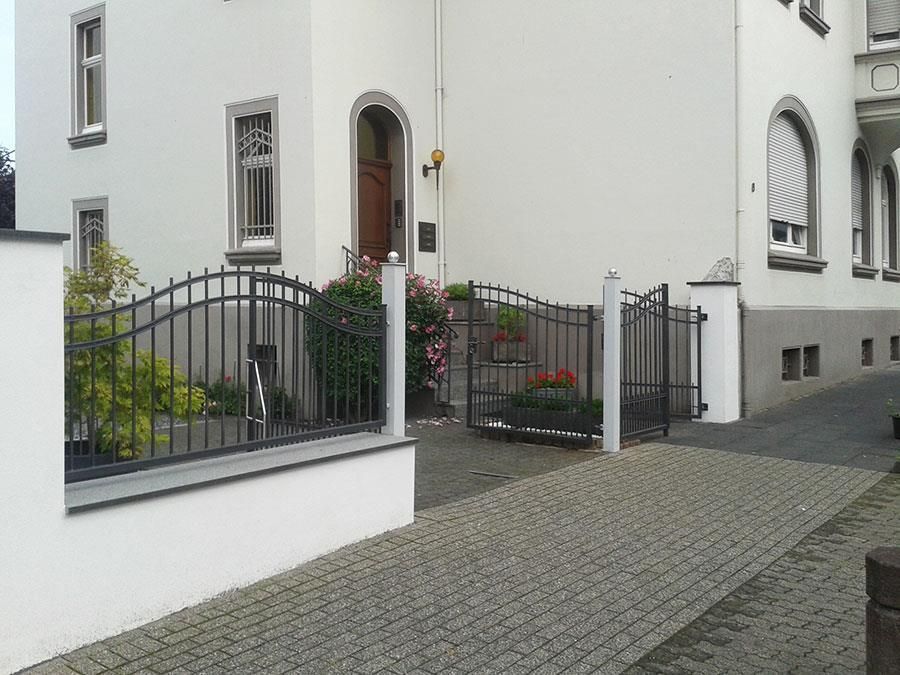 Ein weißes Haus mit einem schmiedeeisernen Zaun darum