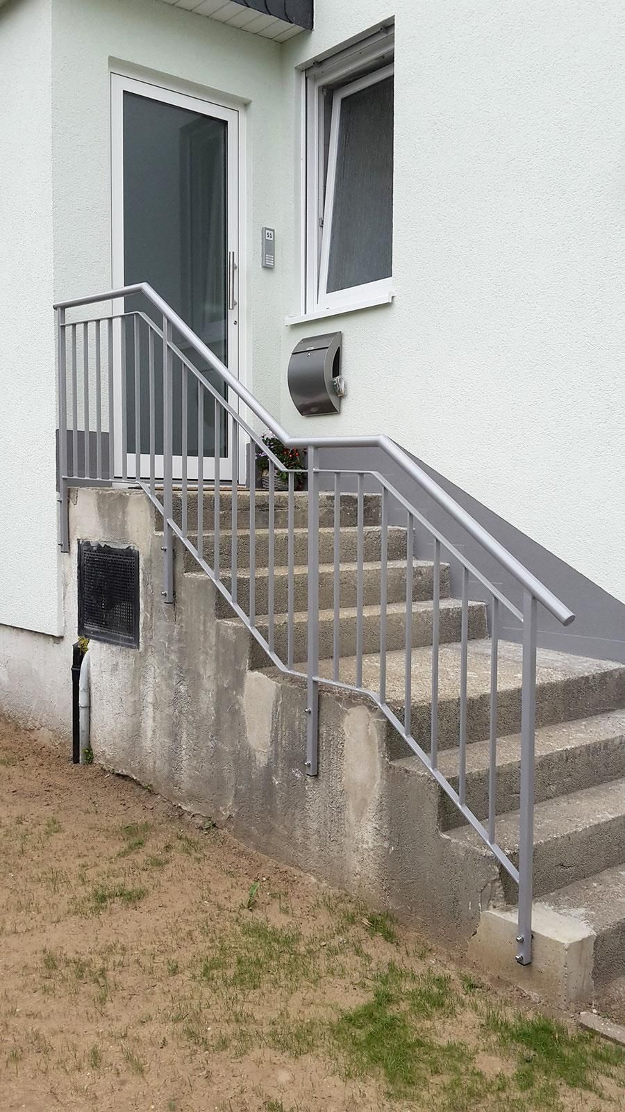 Ein weißes Haus mit einer Treppe, die hinaufführt, und einem Metallgeländer.