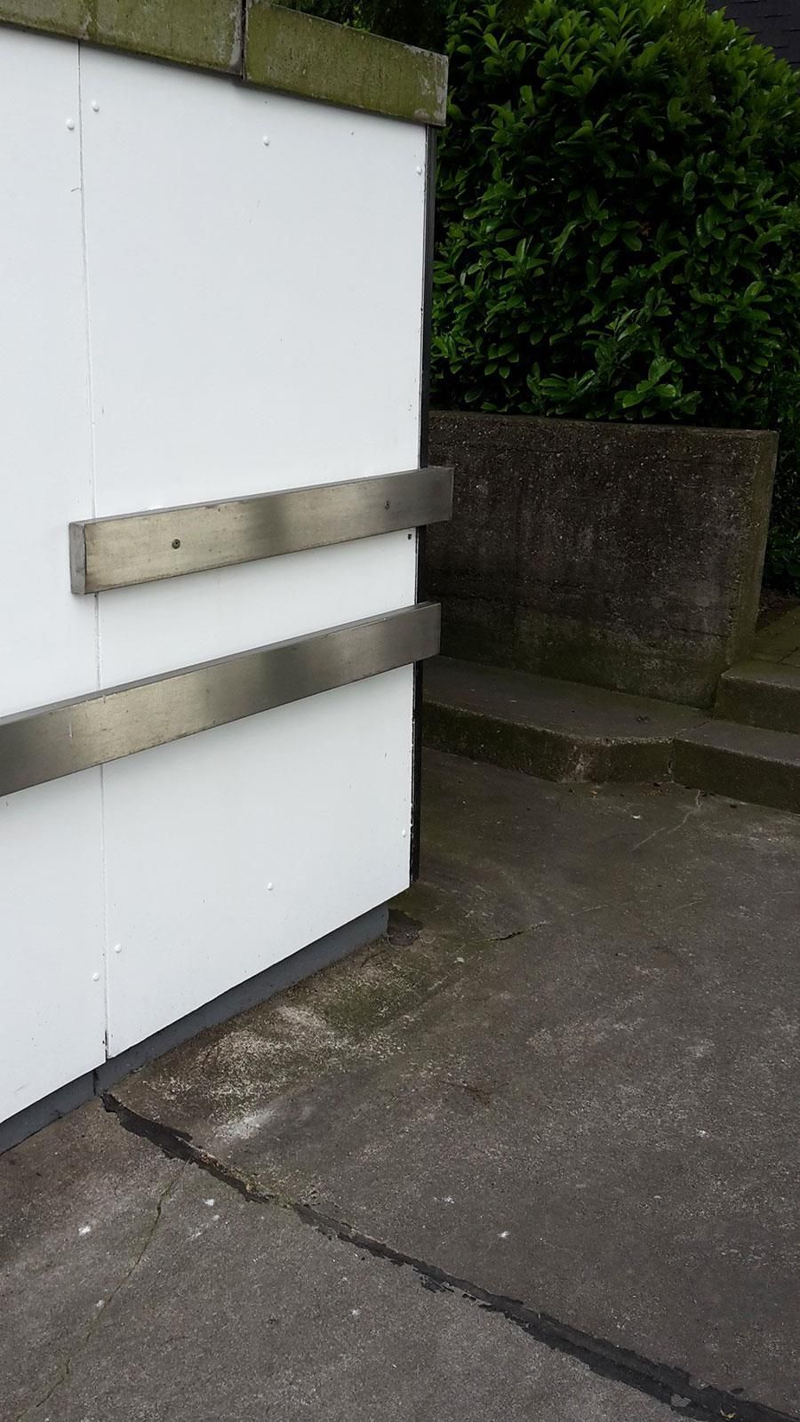 Eine weiße Wand mit einem Edelstahlgeländer an der Seite.