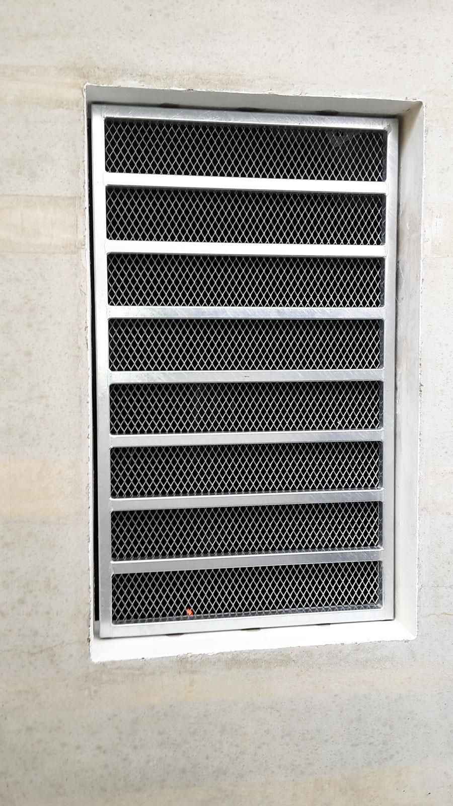 In einer Wand befindet sich ein Fenster mit einem Metallgitter.
