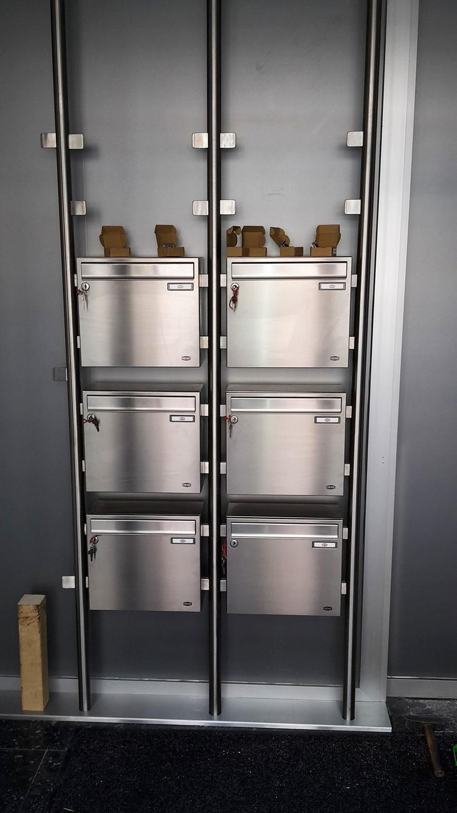 Eine Reihe von Briefkästen aus Edelstahl an einer Wand