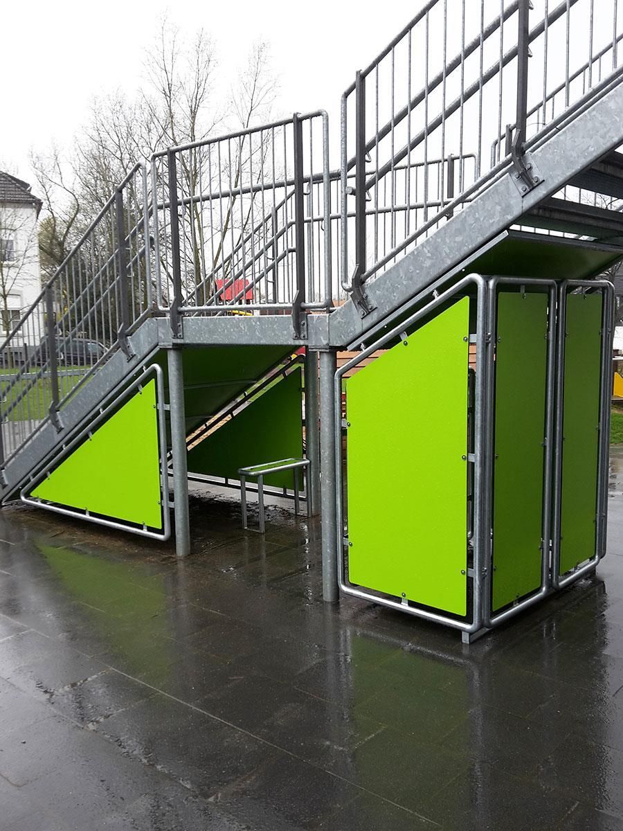 Eine Treppe mit grünen Kisten darunter.