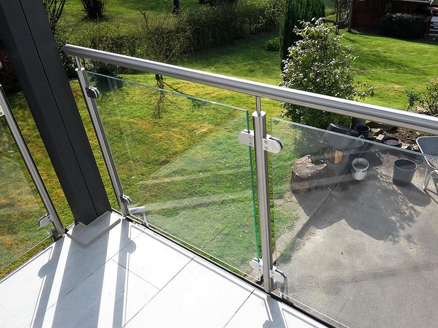 Ein Balkon mit Glasgeländer und Blick auf einen Garten.