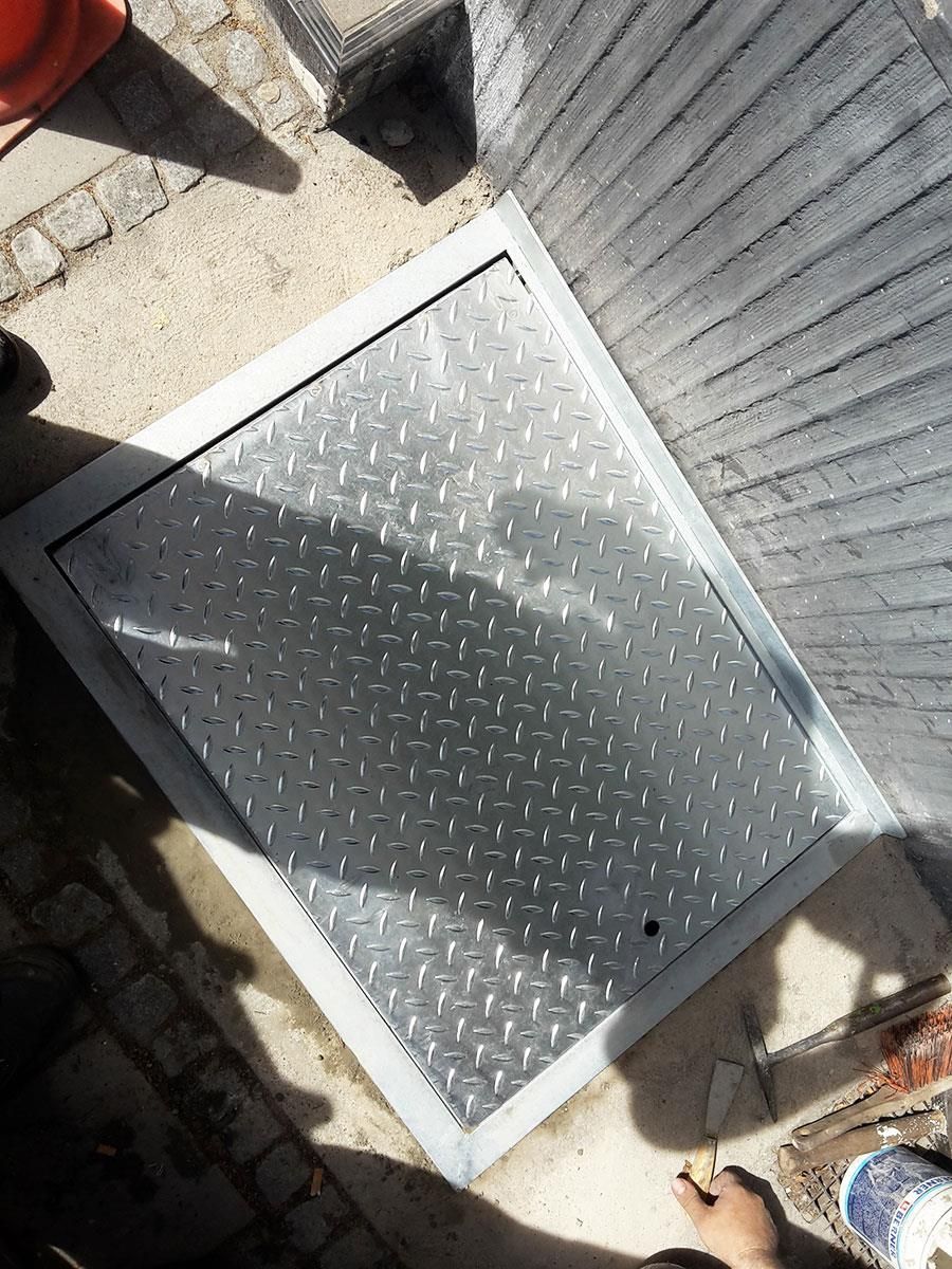 Ein Kanaldeckel liegt auf dem Boden neben einer Ziegelmauer