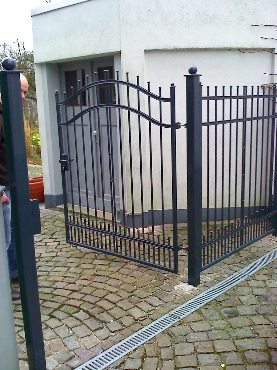 Ein Mann steht vor einem schmiedeeisernen Tor