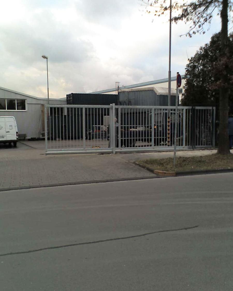 Ein weißer Lieferwagen steht vor einem Gebäude, das von einem Zaun umgeben ist