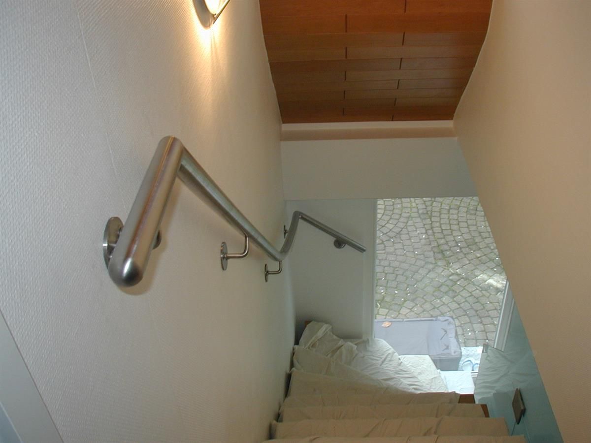 Eine Treppe mit Edelstahlhandlauf und Holzdecke.