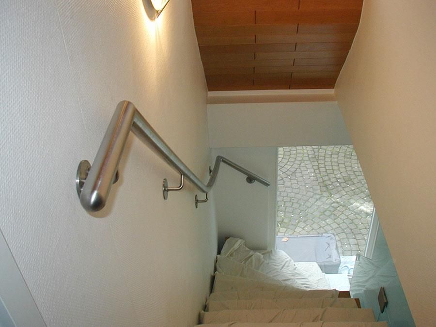 Eine Treppe mit Edelstahlhandlauf und Holzdecke