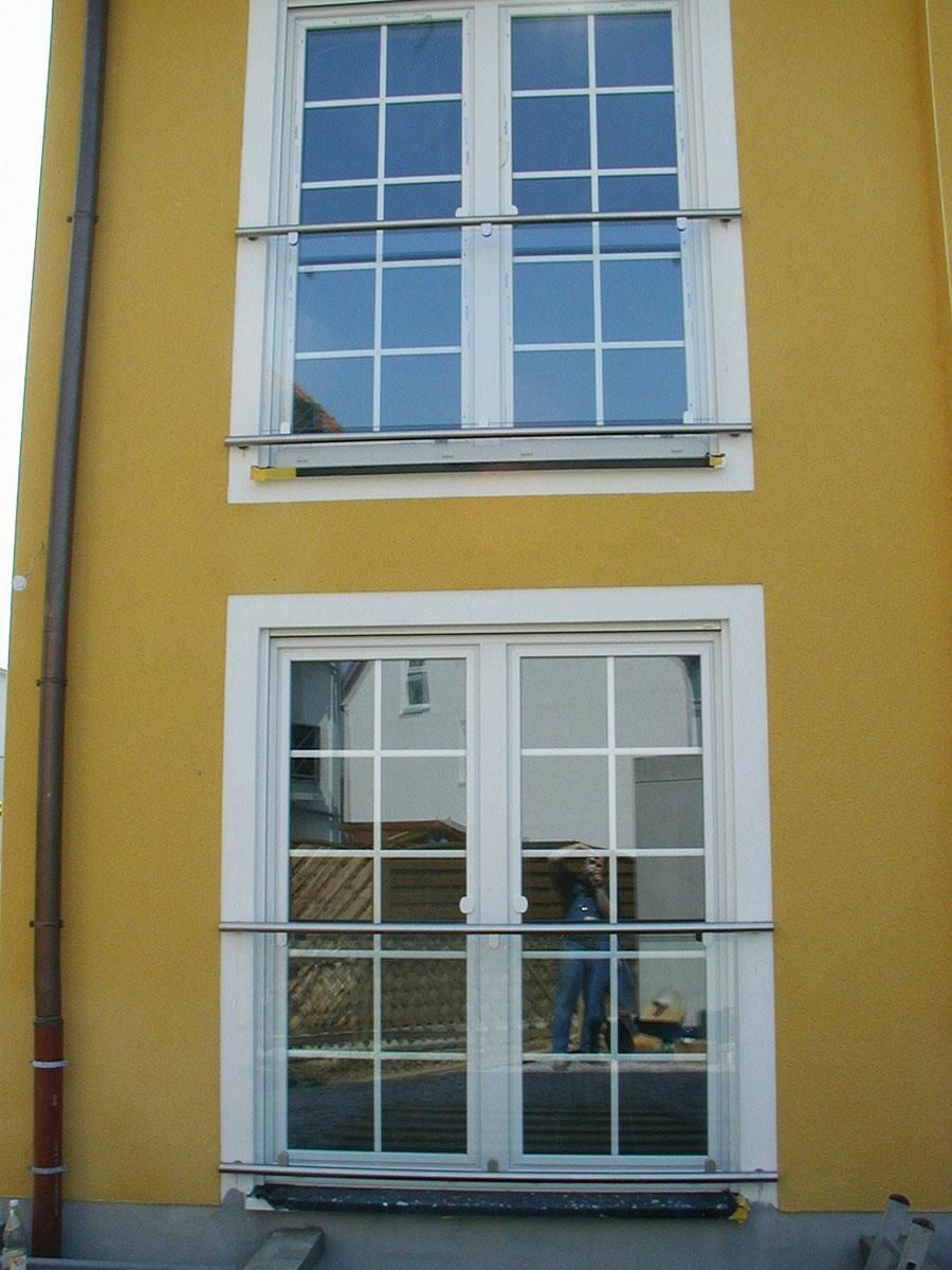 Ein gelbes Gebäude mit der Spiegelung einer Person im Fenster