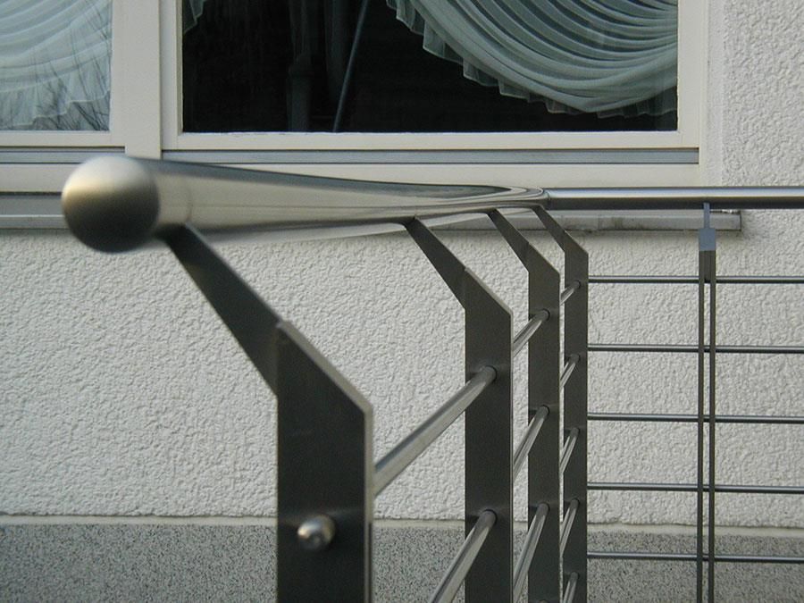 Ein Edelstahlgeländer auf einem Balkon mit einem Fenster im Hintergrund