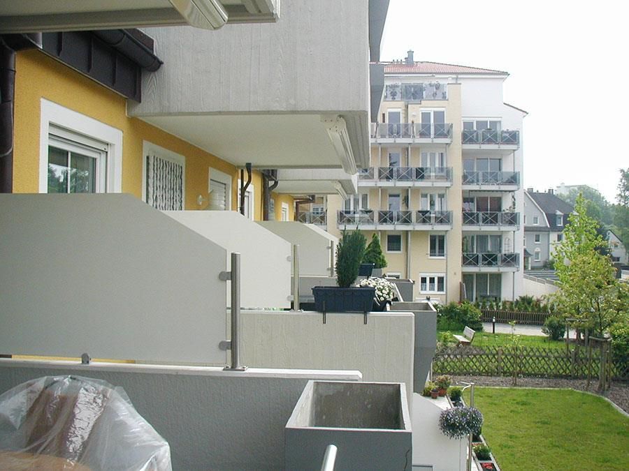 Ein Balkon mit Blick auf ein Gebäude und einen Garten