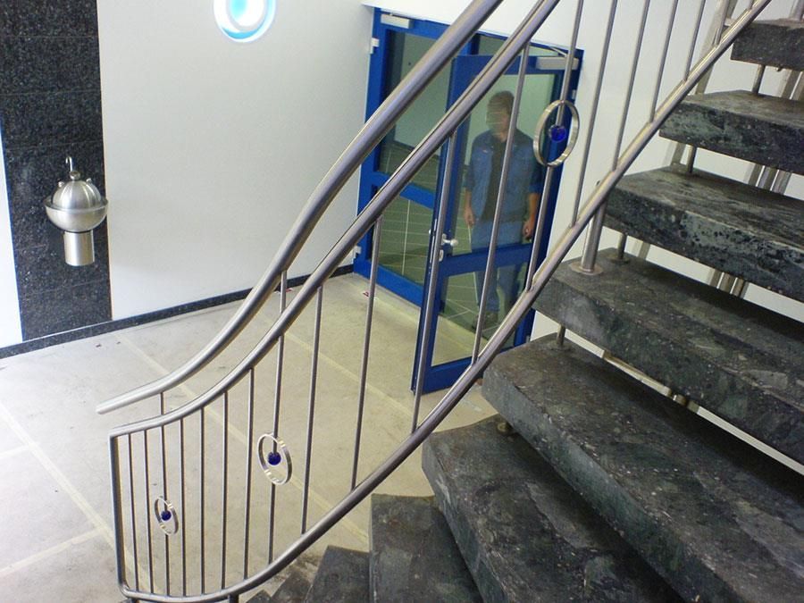 Eine Treppe mit einem Edelstahlgeländer und einer blauen Tür