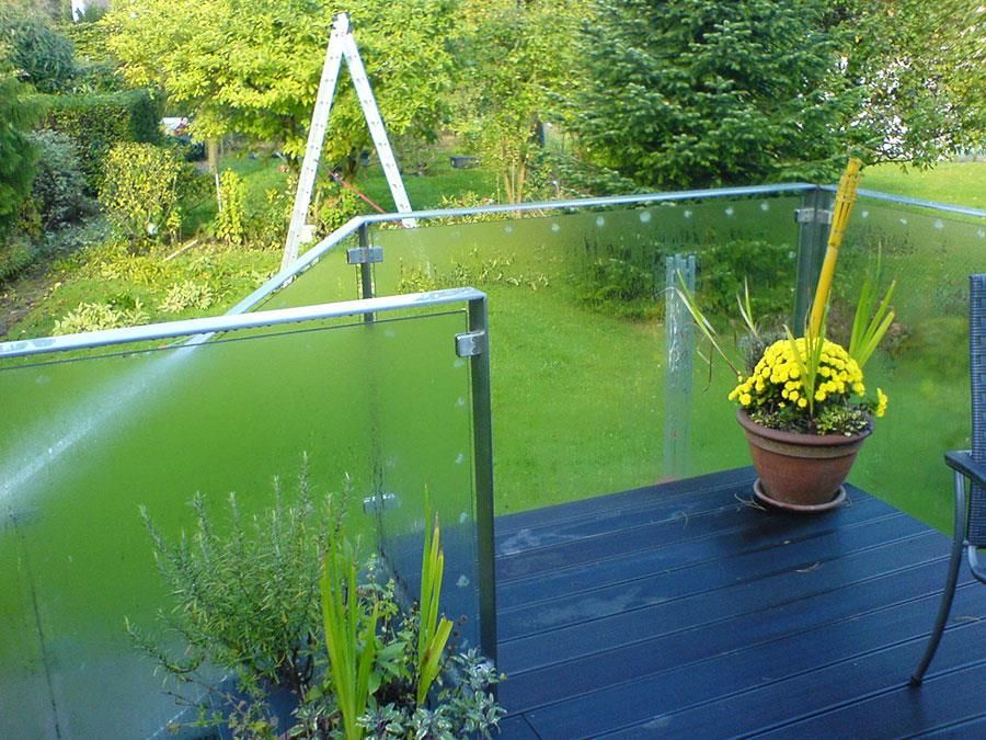 Ein Balkon mit einem Glasgeländer und einem Topf mit gelben Blumen
